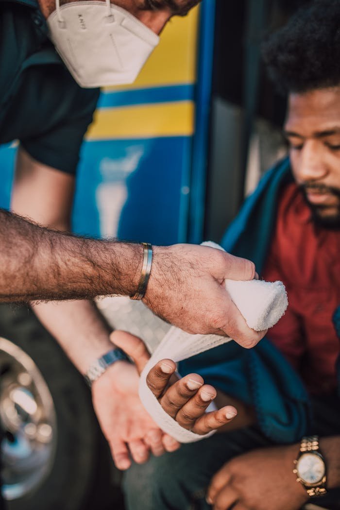 A healthcare worker providing first aid bandaging to an injured mans hand.